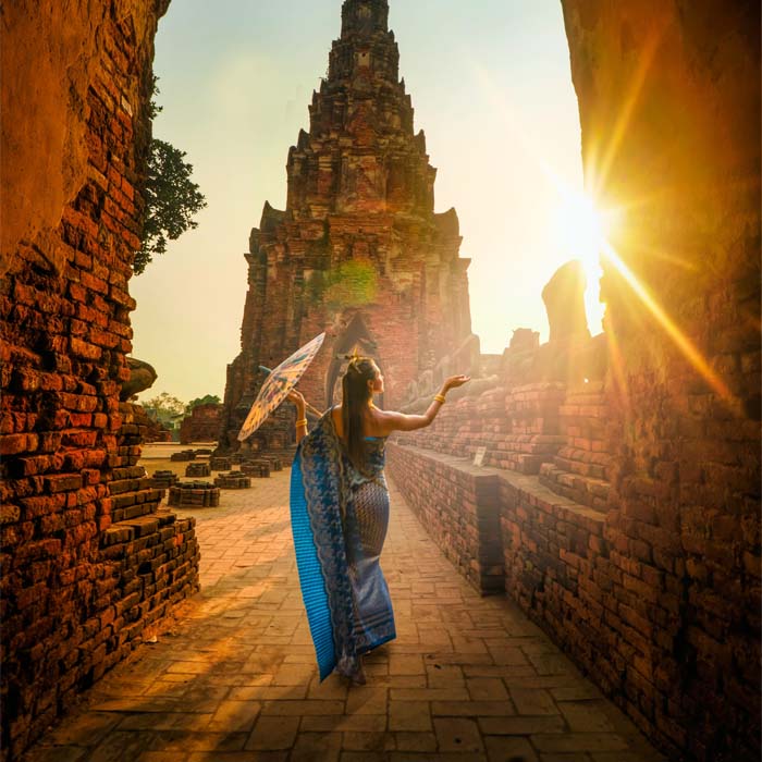 Woman standing in front of an asian temple at sunset