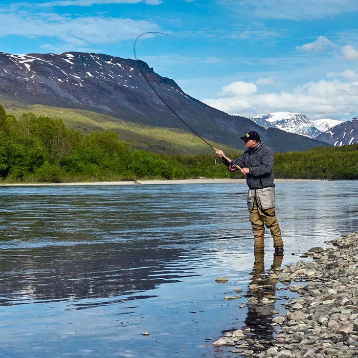 Photo of a man standing in a river and fishing.