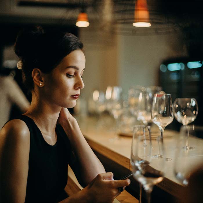a single woman sitting at a bar looking at her phone