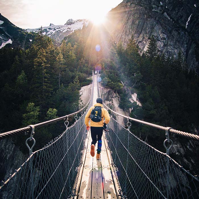 a person jogging along a bridge spanning between two mountains