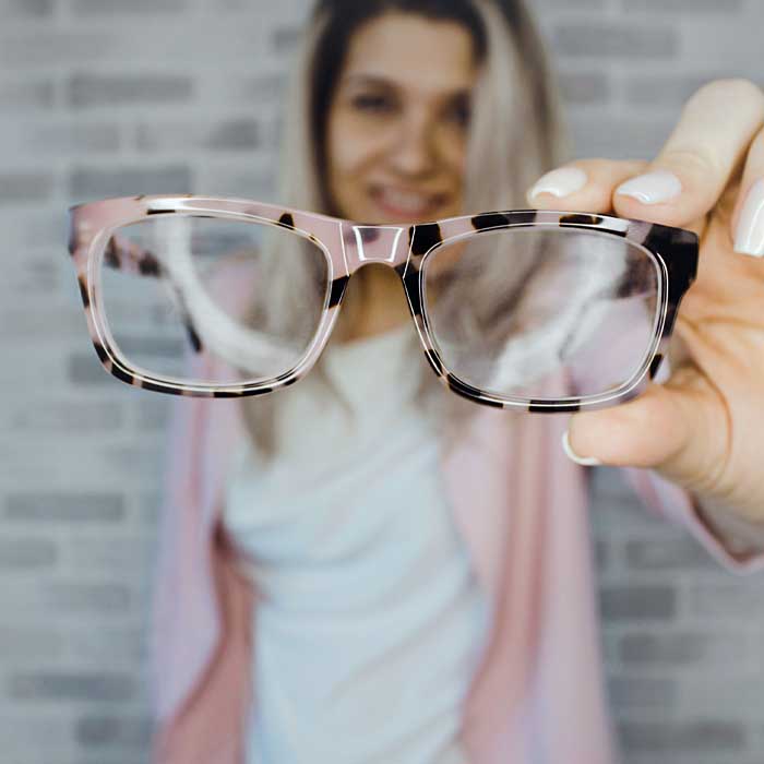 woman holding up a pair of reading glasses