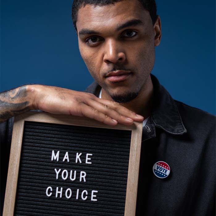 young man holding up a board with the words make your choice on it